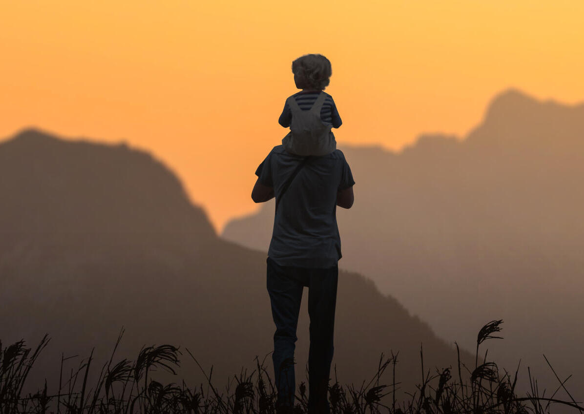 Vater mit Kind auf den Schultern schauen ins Gebirge